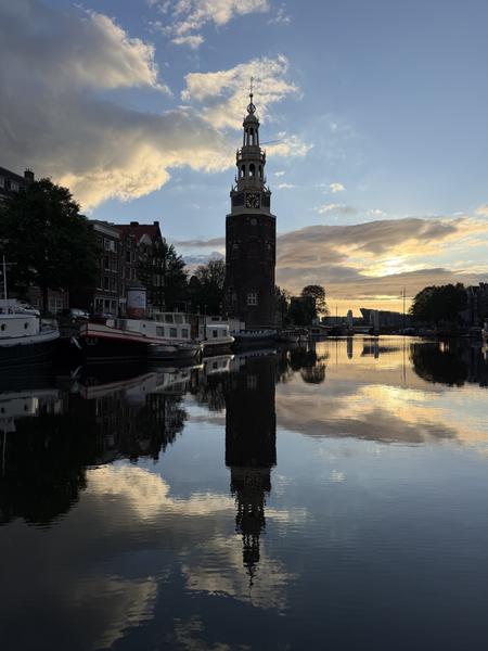 This captivating photo captures the iconic Montelbaanstoren tower perfectly reflected in the tranquil waters of the Oudeschans canal in Centrum, Amsterdam